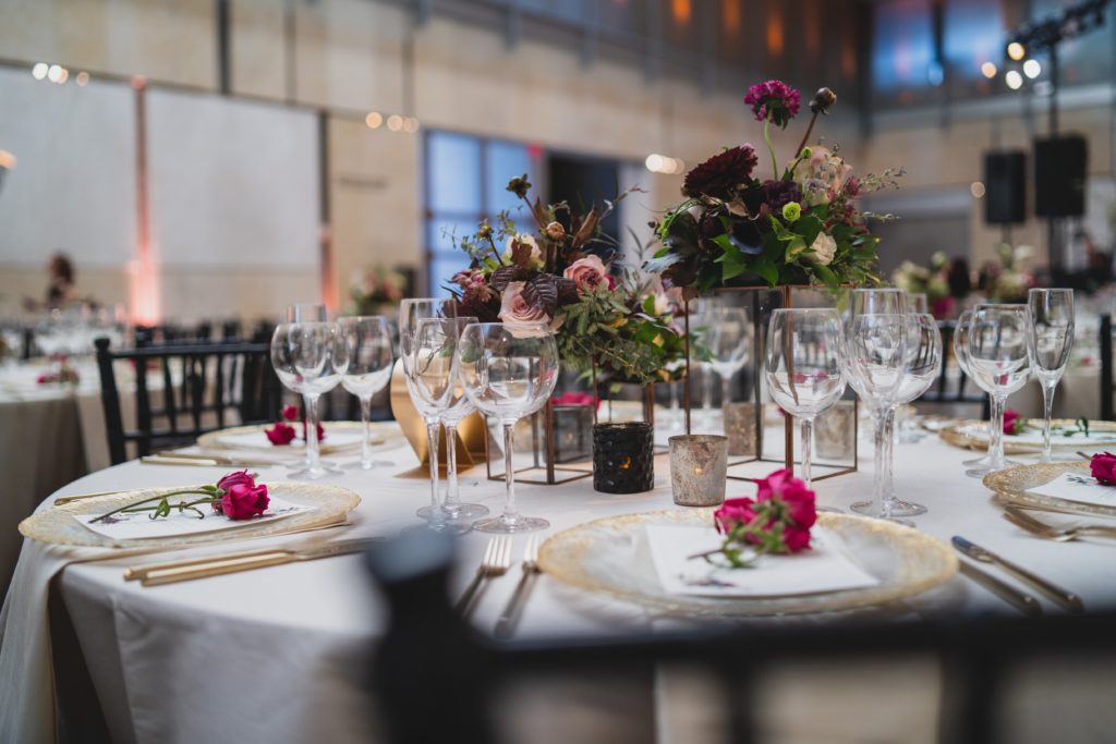 Modern Organic Museum Wedding Reception Centerpiece with contemporary gold and glass risers, garden roses, dahlias, plum colored foliage and lush mixed eucalyptus greenery at the Barnes Foundation by Sebesta Design. Photography by Max Grudzinski Photography 