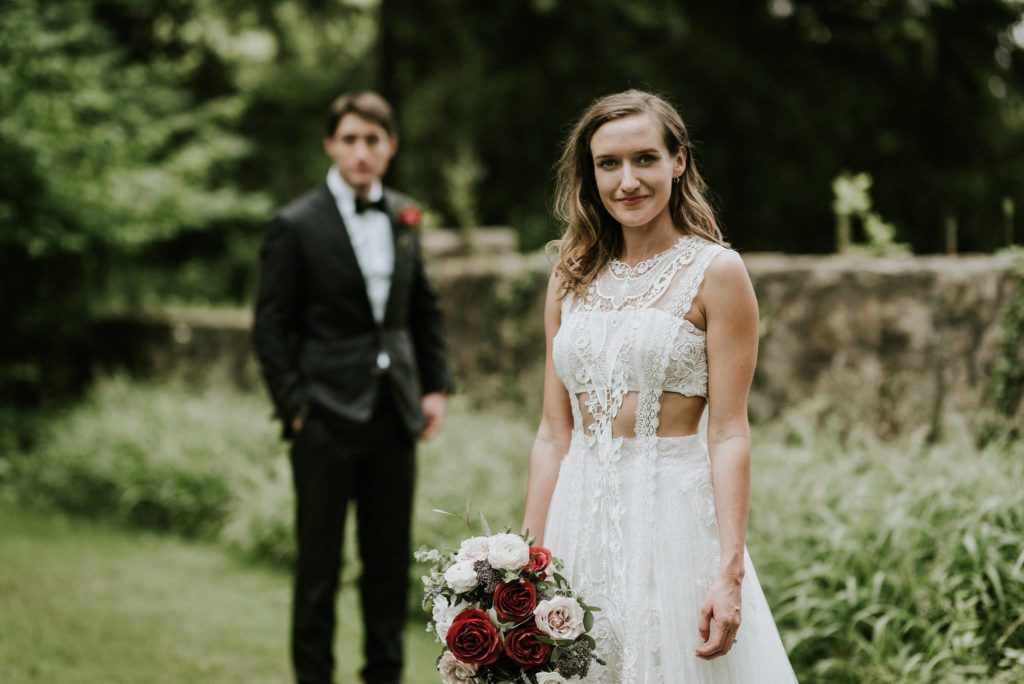 Bride and Groom outdoors at Inn at Barley Sheaf Farm. Bride carrying her garden-inspired old world romantic bouquet with specialty mauve-red roses, garden roses, spray roses and mixed eucalyptus greenery designed by Sebesta Design. Photography by M2 Photography.