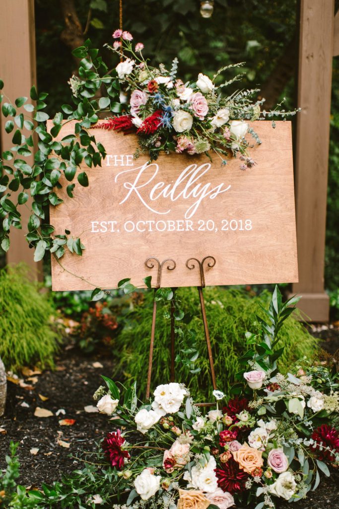 Elegant, Ethereal and Autumnal Pomme Radnor Wedding. Custom welcome sign adorned with smilax vine, blue thistle, garden roses, taupe quickand roses, white majolica spray roses, burgundy astilbe and garden greenery. Designed by Sebesta Design, Photography by Redfield Photography