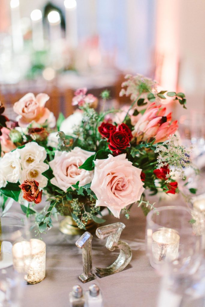 Elegant, Ethereal and Autumnal Pomme Radnor Wedding Reception. Asymmetrical centerpiece in a gold footed compote bowl composed of roses, garden roses, dahilas, lisianthus, anemones, laceflower, spray roses, king protea and garden greens. Designed by Sebesta Design, Photography by Redfield Photography