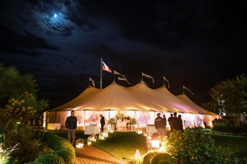 Classic Timeless Garden Party Cape May Congress Hall Wedding at night. Sailcloth tent lawn reception with entrance flanked by lush overflowing garden urns. Lantern-lined garden path. Event design by Sebesta design, photography by Rachel Pearlman Photography