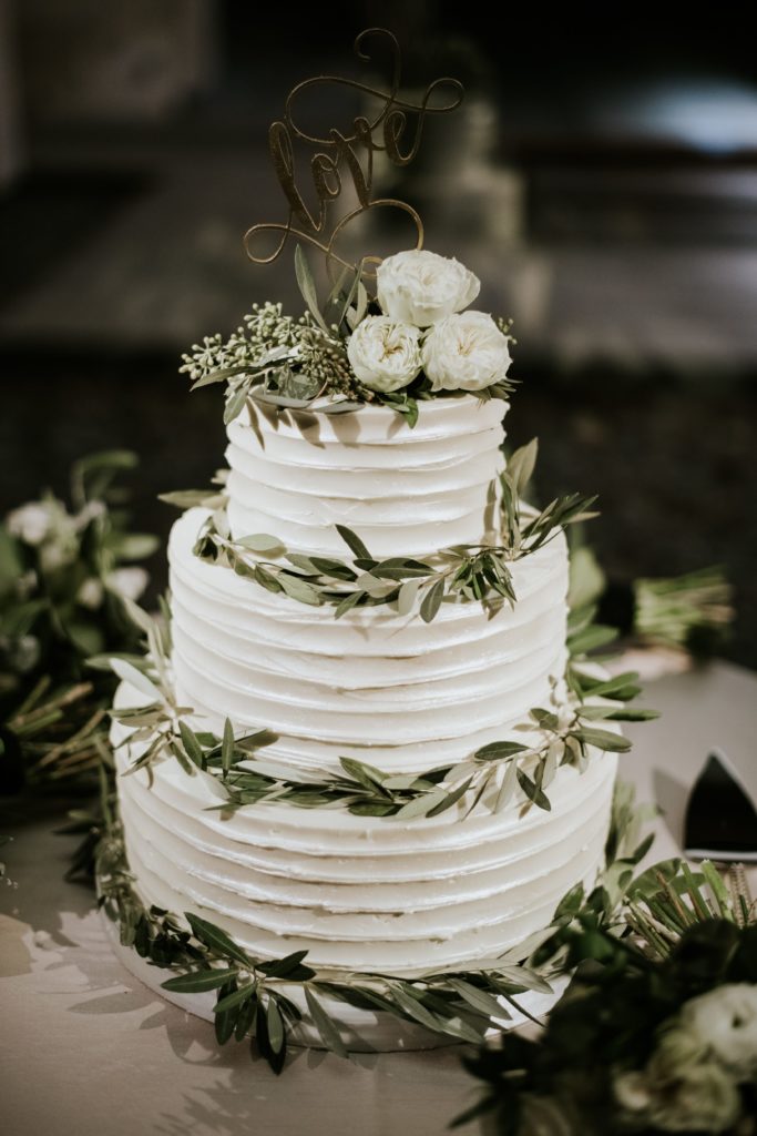 Cake framed by olive branches, garden roses and eucalyptus by Sebesta Design. Photo by M2 Photography