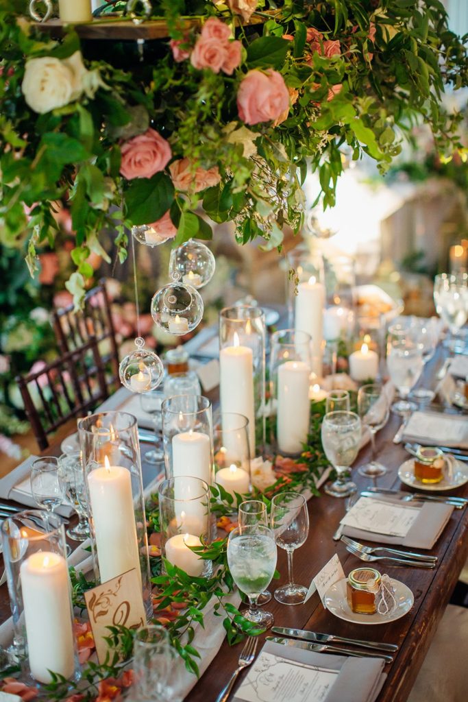 Elegant Secret Garden Wedding Reception, Long Table centerpiece tablescape detail showing multiple pillar candles in varying heights and delicage glass hanging candle globes at The Inn at Barley Sheaf Farm. Designed by Sebesta Design. Photography by Juliana Laury Photography