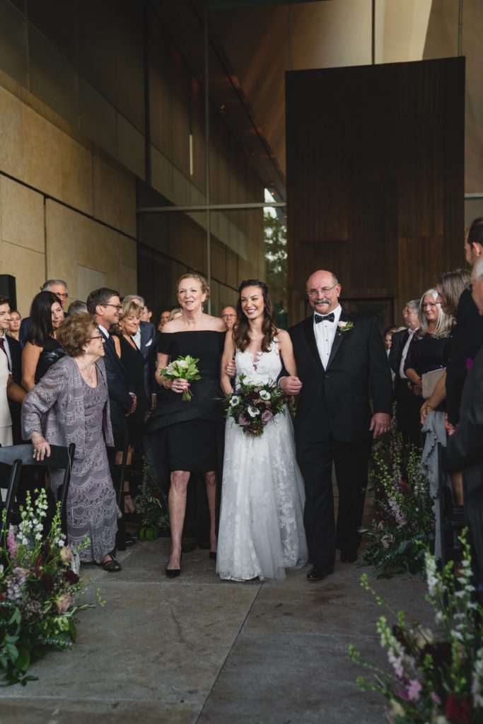 Bride walking down the aisle during Modern Organic Museum Wedding Ceremony with lush garden-inspired aisle decor at the Barnes Foundation by Sebesta Design. Photography by Max Grudzinski Photography