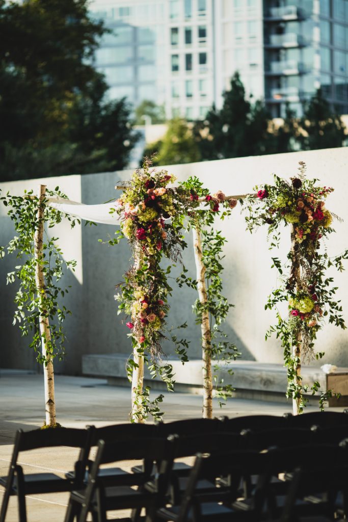 Modern Organic Museum Wedding Ceremony Birch Chuppah entirely covered with wild smilax vine and flowers outdoors at the Barnes Foundation by Sebesta Design. Photography by Max Grudzinski Photography 