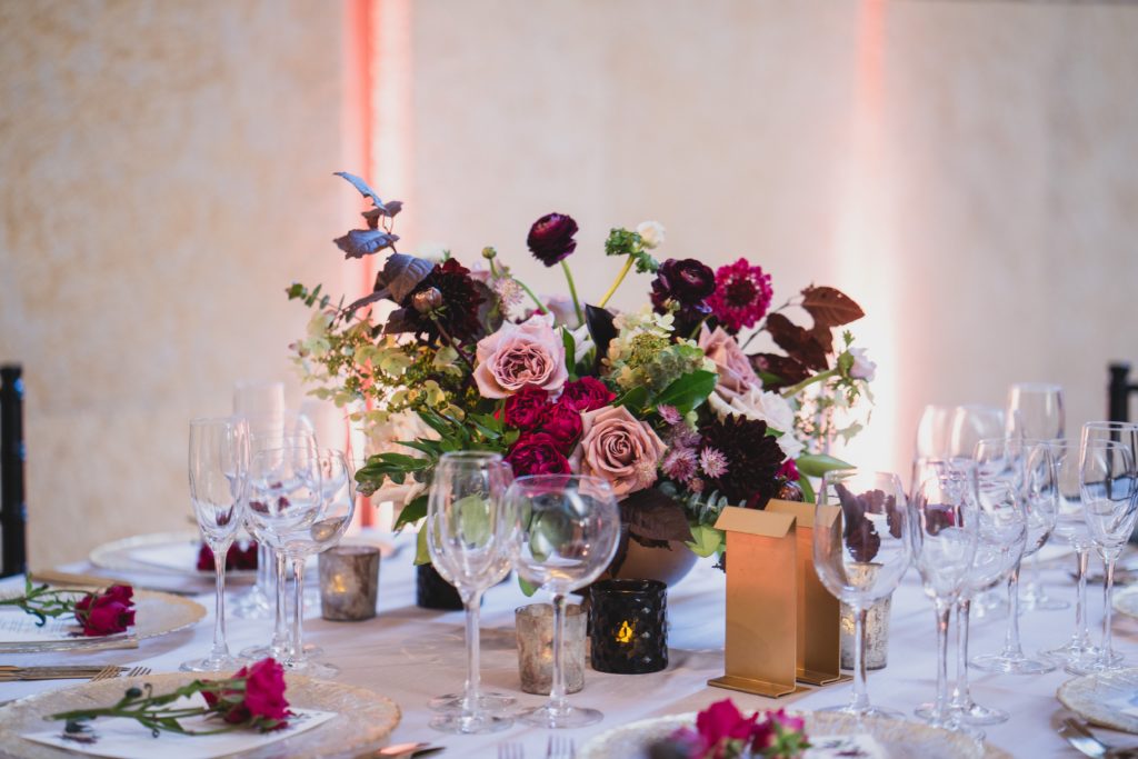 Modern Organic Museum Wedding Reception Compote Centerpiece with garden roses, black dahlias, scabiosa, ranunculus and mixed foliage including moody, dark plum-colored accents at the Barnes Foundation by Sebesta Design. Photography by Max Grudzinski Photography 