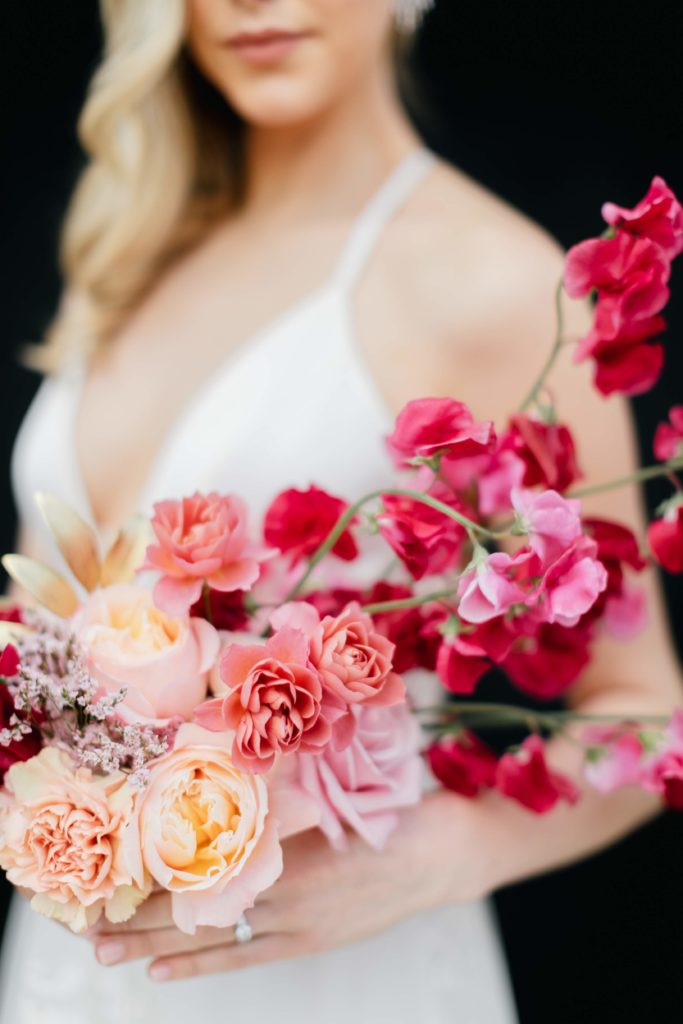 Love is in the Air styled shoot and bespoke bridal event at the Horticulture Center, avant garde horizontal bouquet detail featuring coral spray roses, hot pink sweet peas and peach garden roses. Event design and florals by Sebesta Design. Photography by Emily Wren Photography.