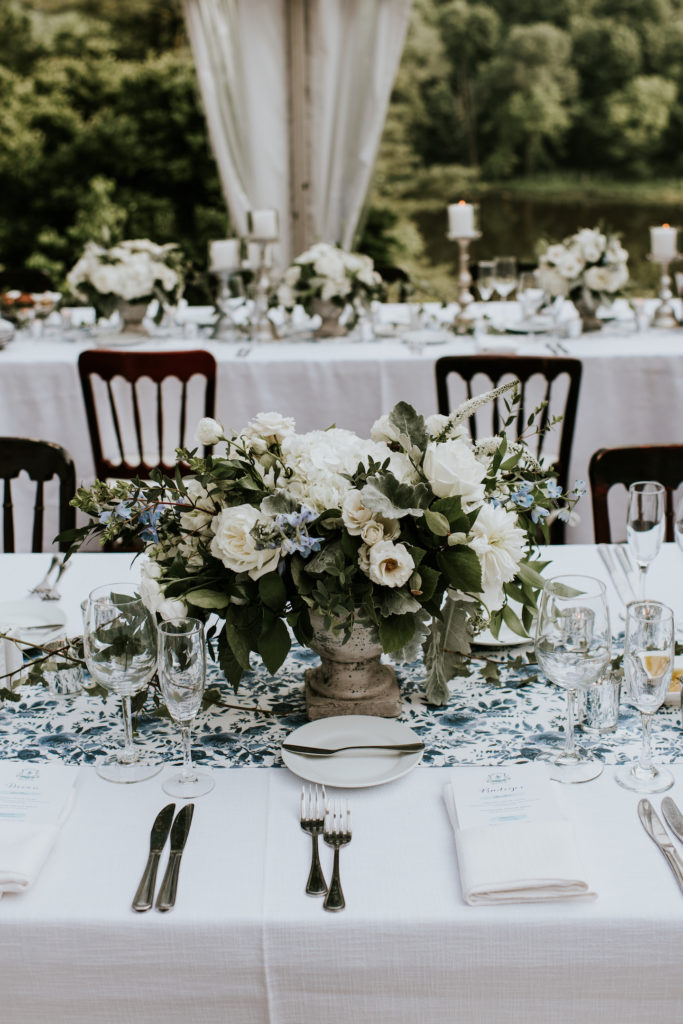 Spring English Garden Welkinweir Wedding Reception. Long table centerpiece in a stone urn featuring peonies, hydrangea, white majolica spray roses, lysimachia, lisianthus, delphinium, garden greens and ivy. Designed by Sebesta Design, Photography by M2 Photography.