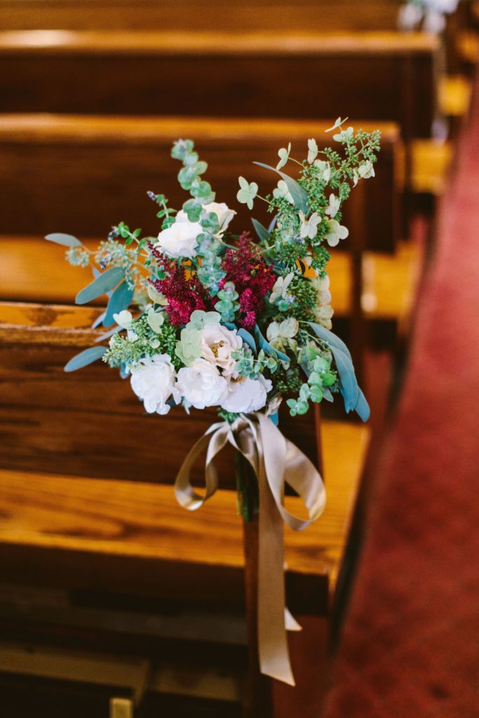 Elegant, Ethereal and Autumnal St. John Neumann Catholic Church Wedding Ceremony. Pew end featuring tardiva hydrangea, white majolica spray roses, burgundy astilbe and garden greenery Designed by Sebesta Design, Photography by Redfield Photography