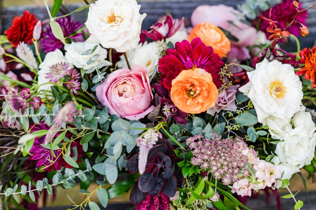 Bold Boho Organic Bridal Bouquet Detail featuring orchids, garden roses, dahlias, chocolate lace flower, spray roses, ranunculus, plume celosia, hanging amaranthus and garden foliage with matching floral bridal head wreath designed by Sebesta Design. Photographed by The Caffeinated Photographer.