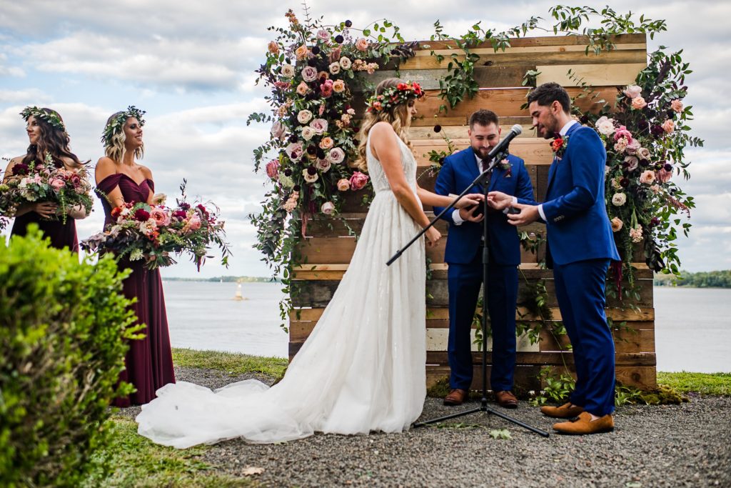 Bold Boho Organic Wedding ceremony at Glen Foerd on the Delaware with custom reclaimed wood pallet backdrop covered in flowers, designed by Sebesta Design and Photographed by The Caffeinated Photographer.